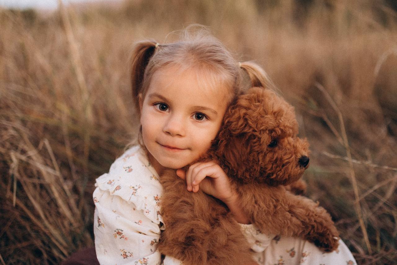 A young daughter cuddling Luna in a field