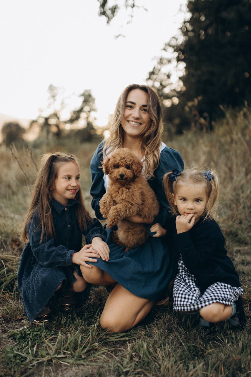 The mother, her daughters, and Luna sitting together outdoors