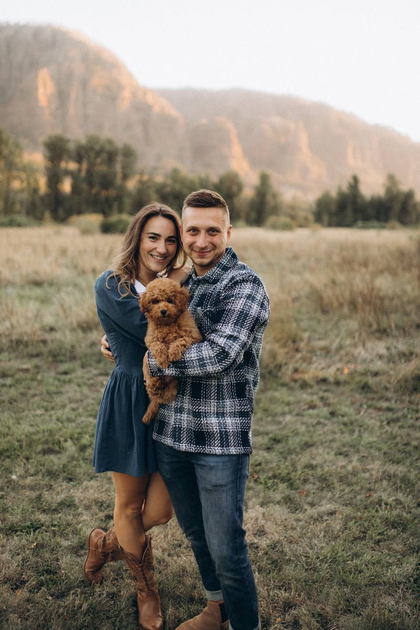 The couple holding Luna in a meadow near Vancouver